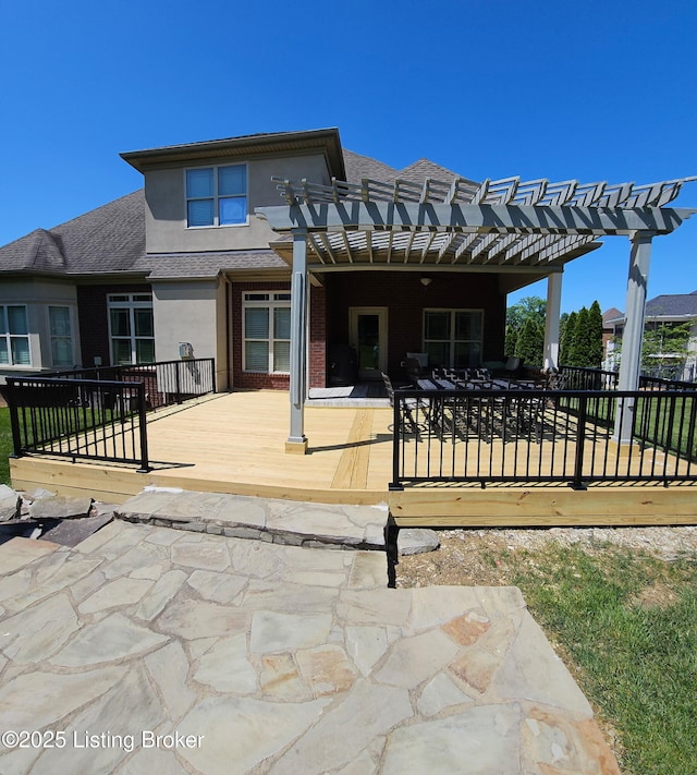 back of house with a pergola, stucco siding, a wooden deck, and a patio