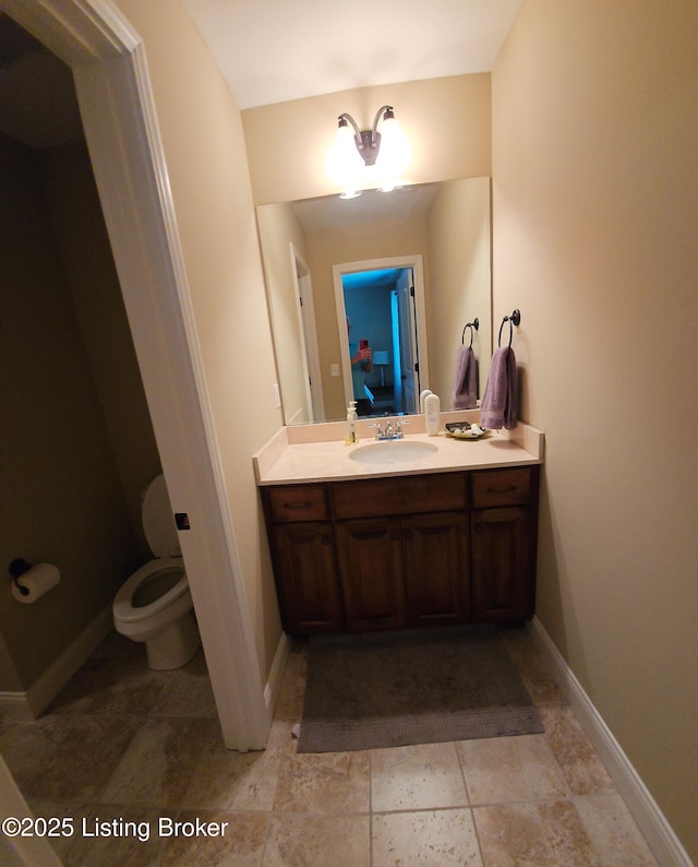 bathroom with vanity, toilet, baseboards, and ensuite bathroom