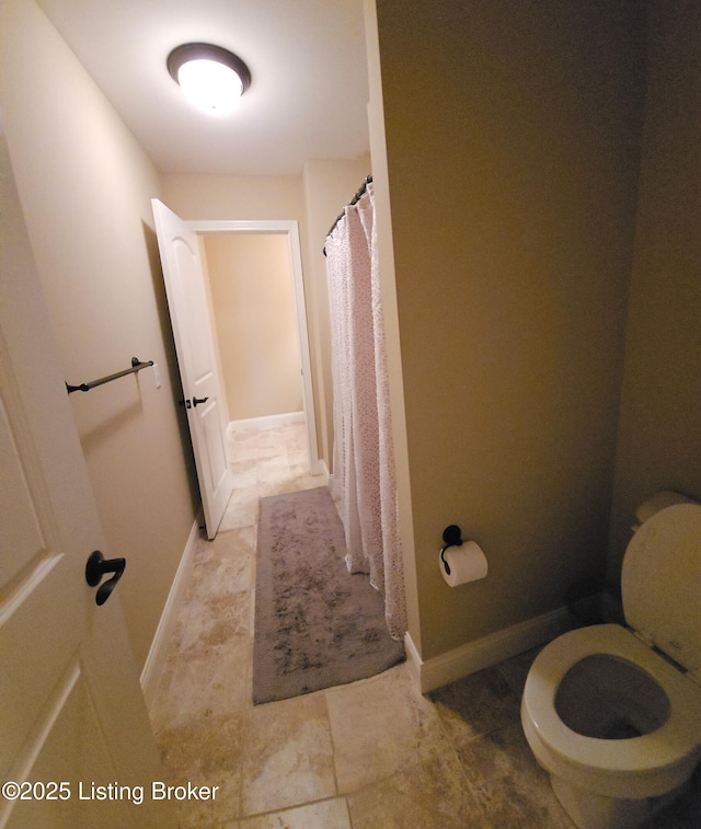 full bath with toilet, baseboards, and curtained shower