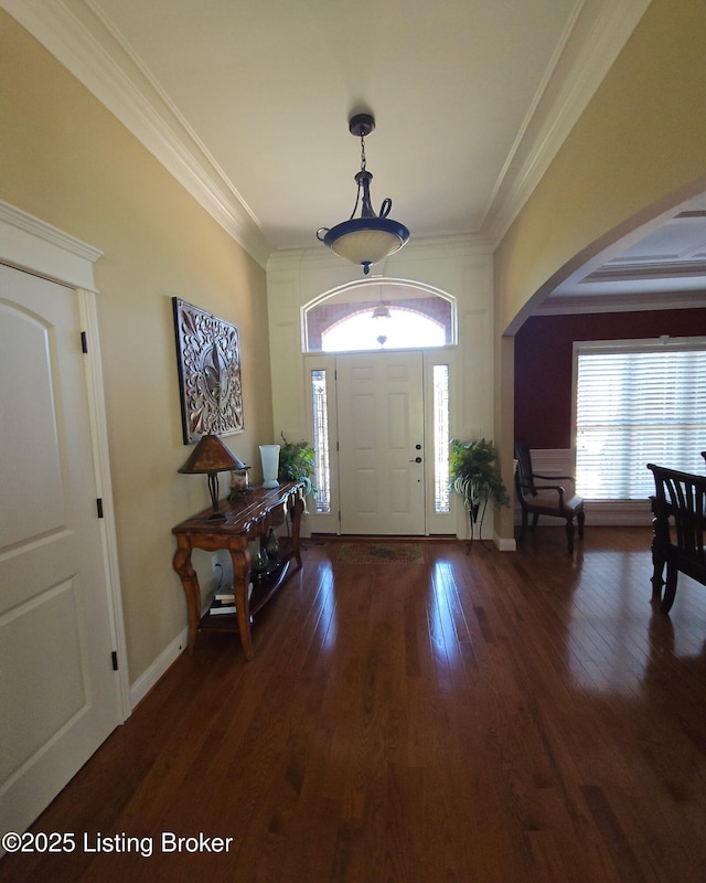 entryway with crown molding, arched walkways, healthy amount of natural light, and dark wood-type flooring
