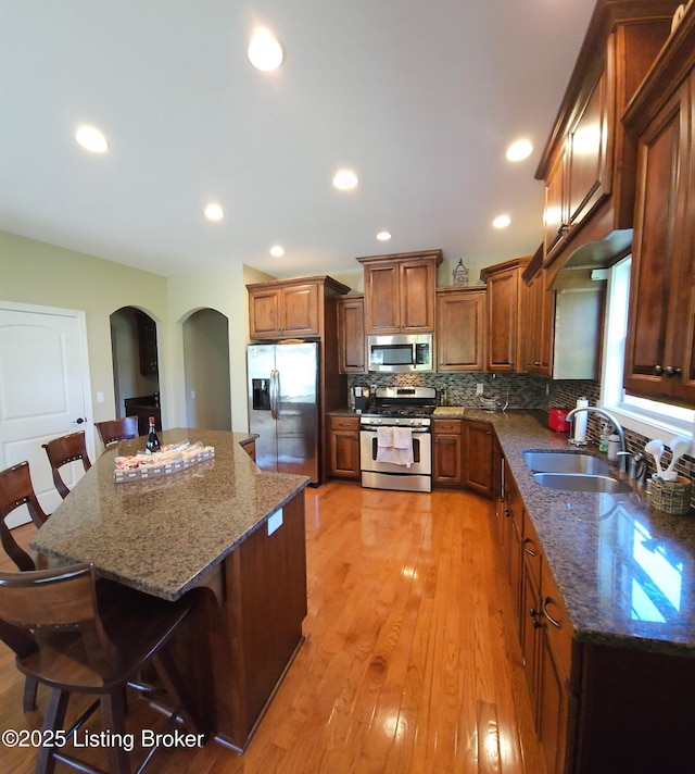 kitchen with stainless steel appliances, arched walkways, a breakfast bar, recessed lighting, and backsplash