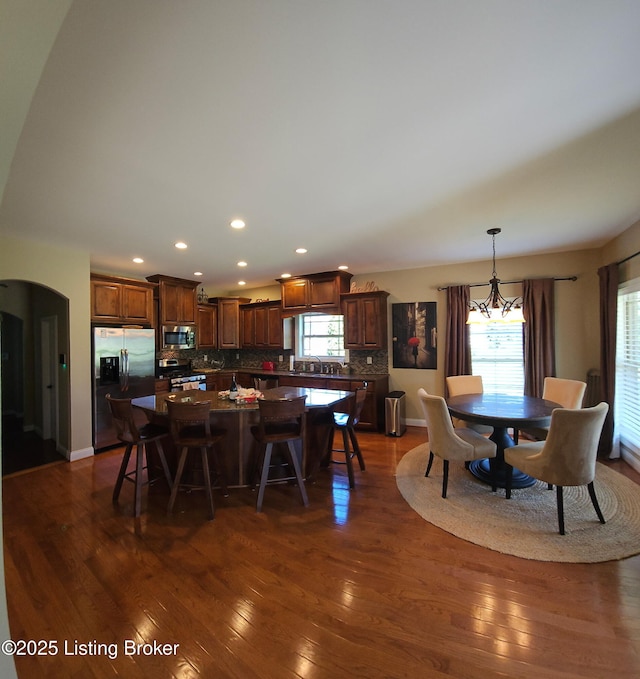 dining space featuring recessed lighting, dark wood-style flooring, plenty of natural light, arched walkways, and a chandelier