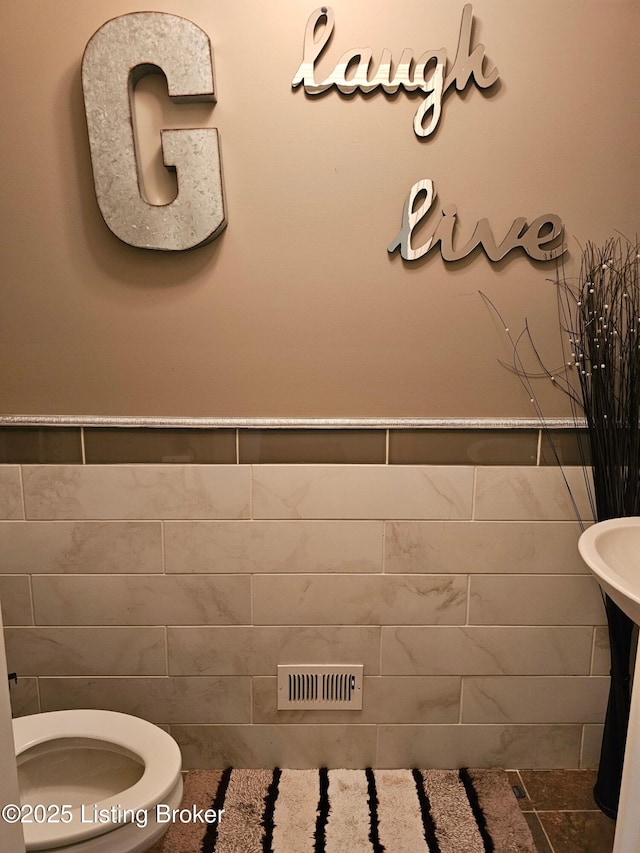 half bathroom featuring toilet and tile walls