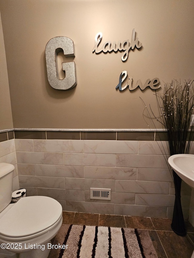 905 Fossil Creek Cir, Louisville, KY 40245 - bathroom featuring toilet, tile walls, and a wainscoted wall