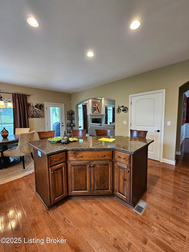 905 Fossil Creek Cir, Louisville, KY 40245 - kitchen with arched walkways, light wood-type flooring, a center island, dark stone counters, and recessed lighting