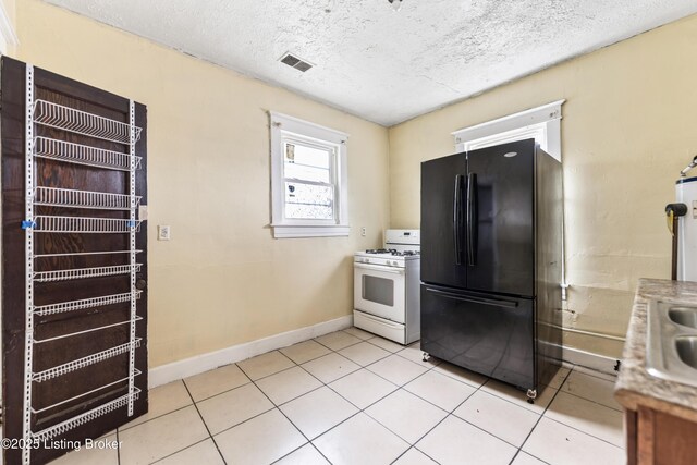 1724 W Ormsby Ave, Louisville, KY 40210 - kitchen with freestanding refrigerator, white gas range oven, baseboards, light tile patterned flooring, and a textured ceiling