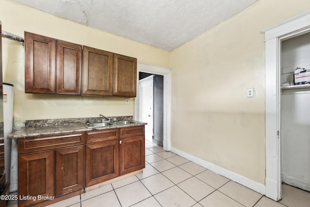 1724 W Ormsby Ave, Louisville, KY 40210 - kitchen featuring a sink, light tile patterned floors, a textured ceiling, baseboards, and dark countertops