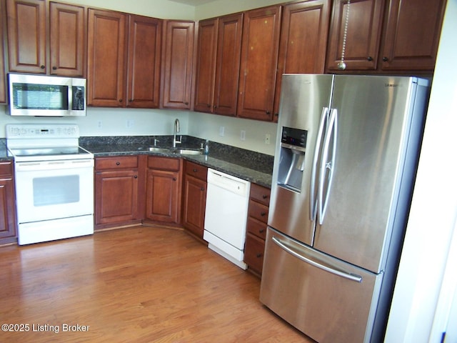 1411 Amberlin Ln, Louisville, KY 40245 - kitchen with stainless steel appliances, a sink, light wood finished floors, dark stone countertops, and brown cabinetry