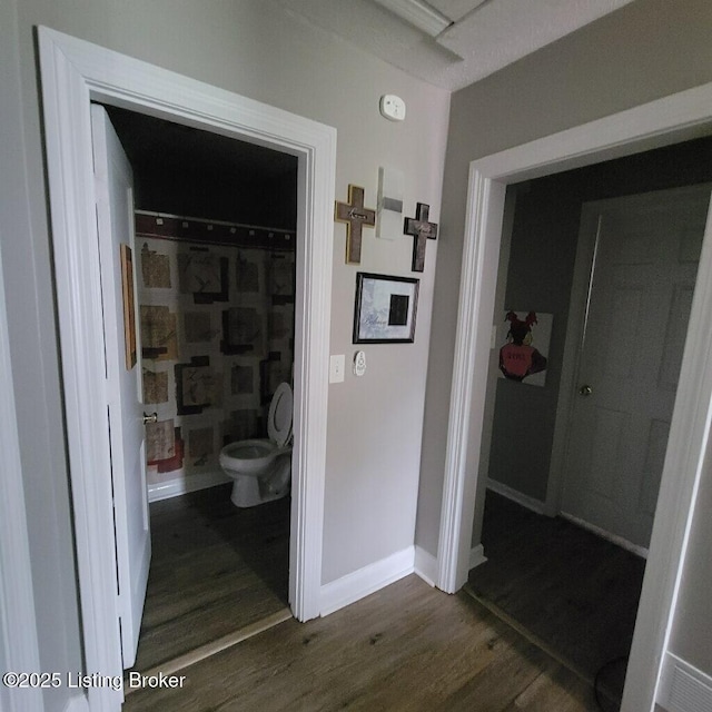 hall with dark wood-style flooring and baseboards