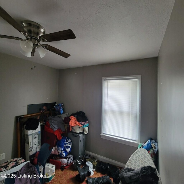 bedroom with ceiling fan, a textured ceiling, and baseboards