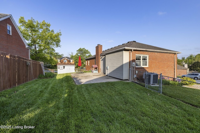 12100 Edenwood Dr, Louisville, KY 40243 - rear view of house featuring brick siding, cooling unit, a patio area, an outbuilding, and a chimney