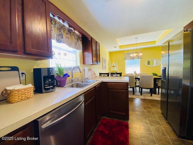 kitchen with stainless steel appliances, light countertops, a sink, and a chandelier