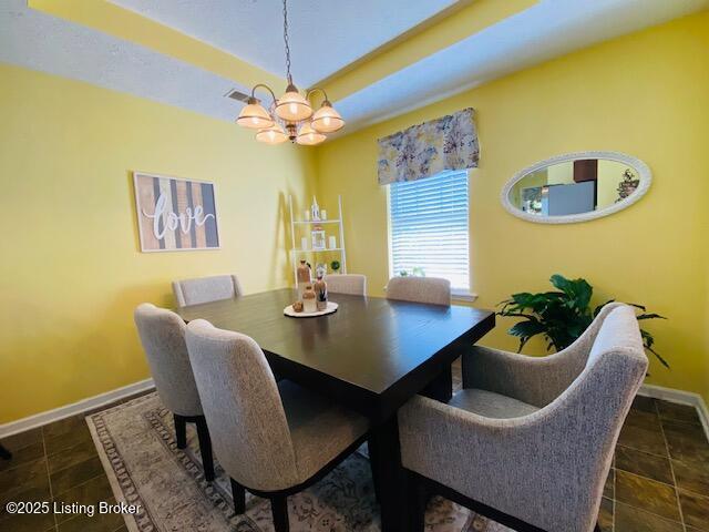 dining space featuring a chandelier and baseboards