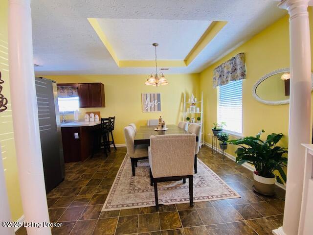 dining area featuring plenty of natural light, a chandelier, baseboards, and decorative columns
