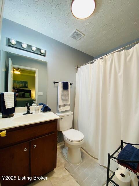 bathroom featuring vanity, toilet, a textured ceiling, and tile patterned floors