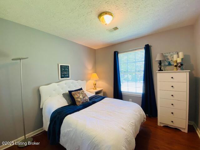 bedroom with baseboards, a textured ceiling, and wood finished floors