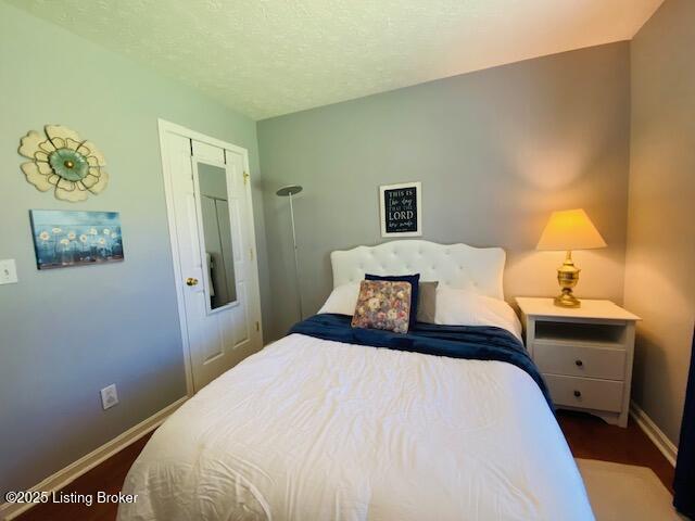 bedroom featuring baseboards, wood finished floors, and a textured ceiling