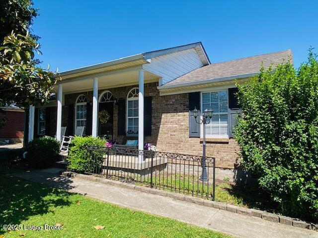 view of front of home with a porch, brick siding, fence, and roof with shingles