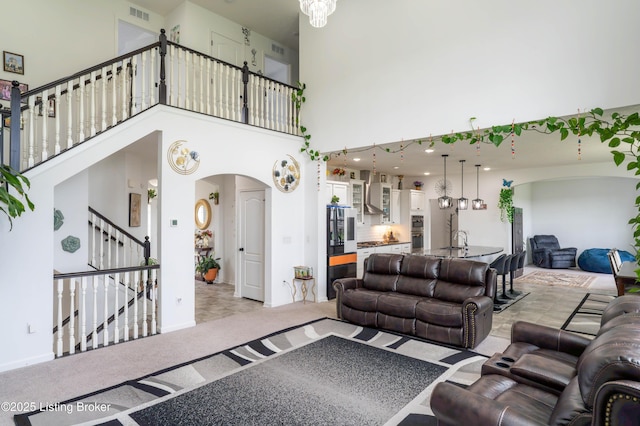 15803 Stonehouse Ct, Louisville, KY 40245 - living area with arched walkways, a high ceiling, stairs, and light carpet
