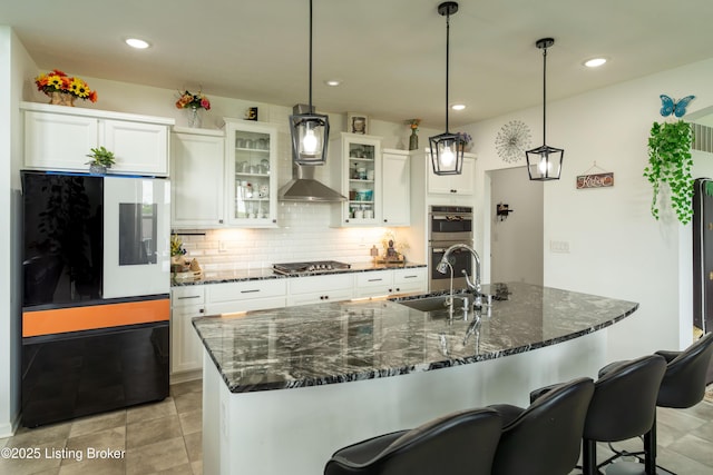 15803 Stonehouse Ct, Louisville, KY 40245 - kitchen with wall chimney exhaust hood, appliances with stainless steel finishes, white cabinetry, decorative backsplash, and a center island with sink