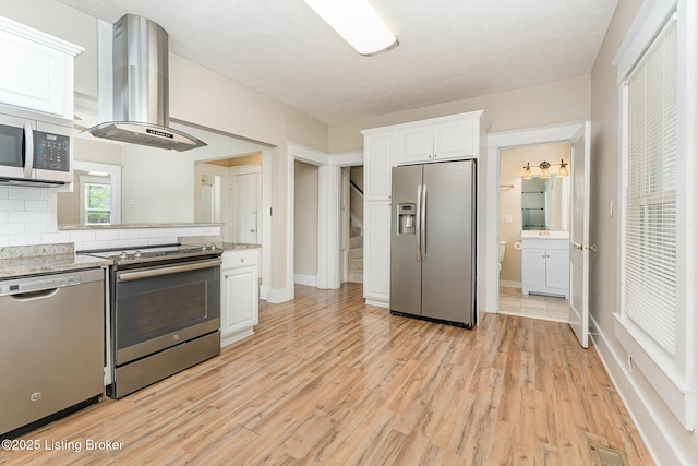 835 Sylvia St, Louisville, KY 40217 - kitchen with appliances with stainless steel finishes, island range hood, backsplash, light wood finished floors, and white cabinets