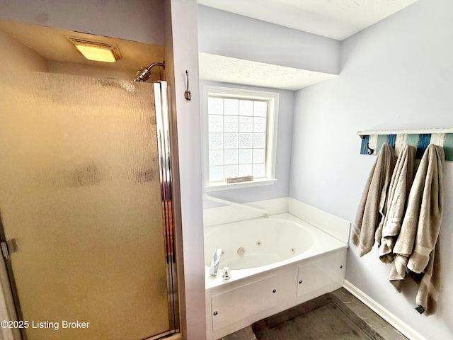full bathroom with a stall shower, a tub with jets, and baseboards