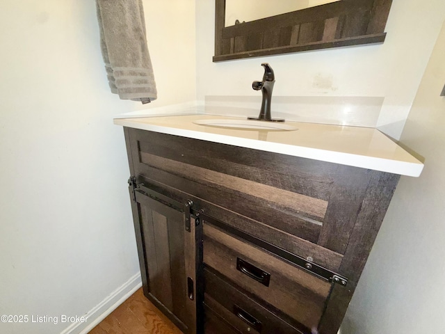 bathroom view of vanity, wood finished floors, and baseboards