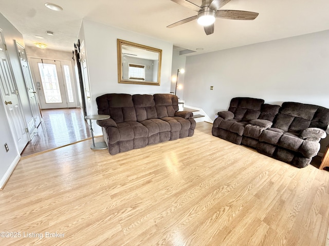 living area featuring wood finished floors, baseboards, and a ceiling fan