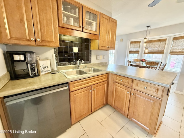kitchen with a sink, stainless steel dishwasher, a peninsula, light countertops, and glass insert cabinets