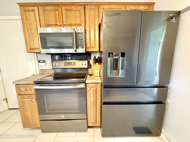 kitchen with appliances with stainless steel finishes, light tile patterned floors, and light countertops