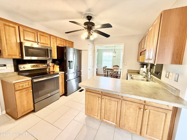 kitchen featuring stainless steel appliances, a sink, a ceiling fan, light countertops, and a peninsula