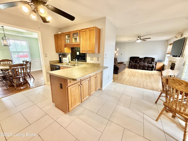 kitchen with ceiling fan, a sink, light countertops, open floor plan, and glass insert cabinets