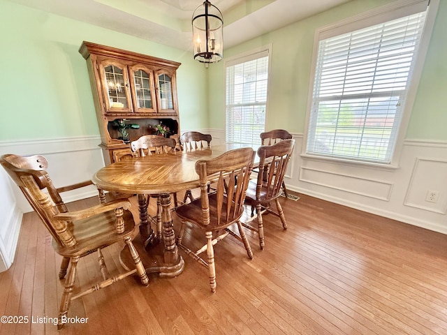 dining area featuring light wood finished floors and a wainscoted wall