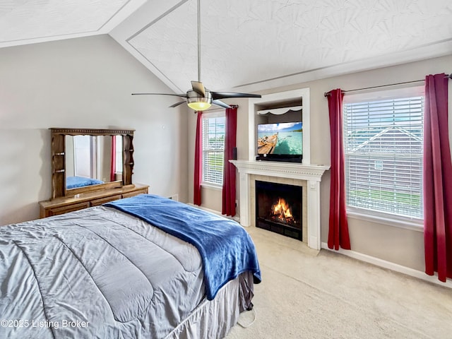 carpeted bedroom featuring a fireplace, ceiling fan, baseboards, and vaulted ceiling