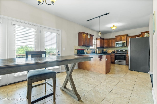 218 Sangria Dr, Vine Grove, KY 40175 - kitchen featuring stainless steel appliances, dark countertops, decorative backsplash, a kitchen breakfast bar, and track lighting