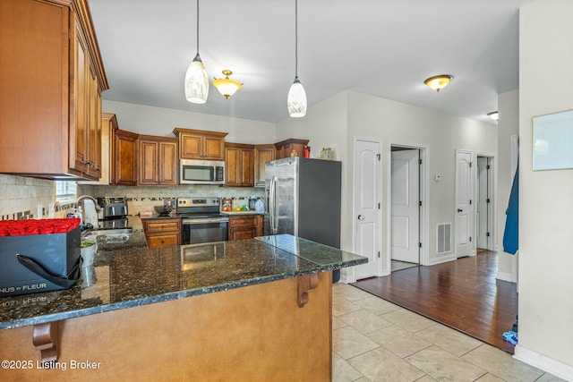218 Sangria Dr, Vine Grove, KY 40175 - kitchen with stainless steel appliances, a sink, a peninsula, brown cabinets, and backsplash