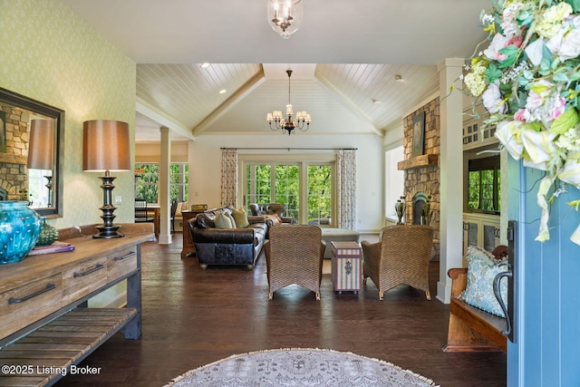 living area featuring lofted ceiling, a chandelier, wood finished floors, wallpapered walls, and a stone fireplace