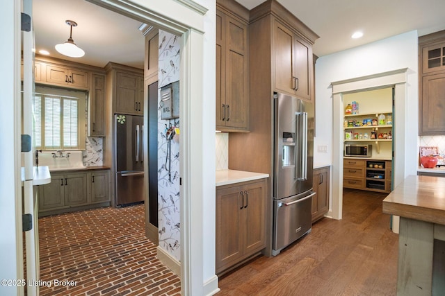 kitchen with stainless steel appliances, decorative backsplash, light countertops, a sink, and recessed lighting