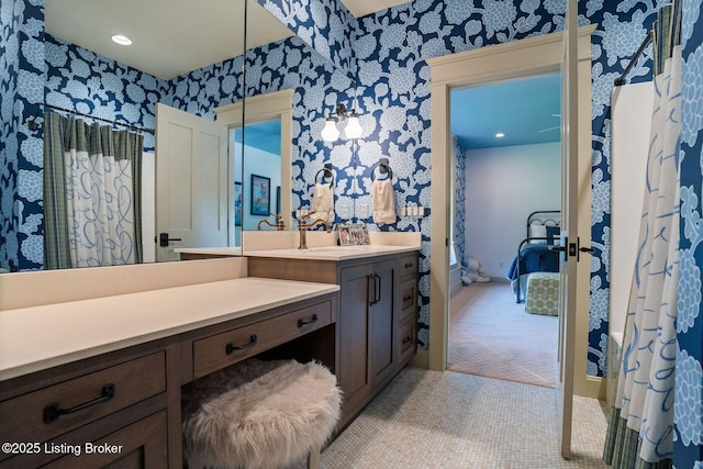 ensuite bathroom featuring wallpapered walls and vanity