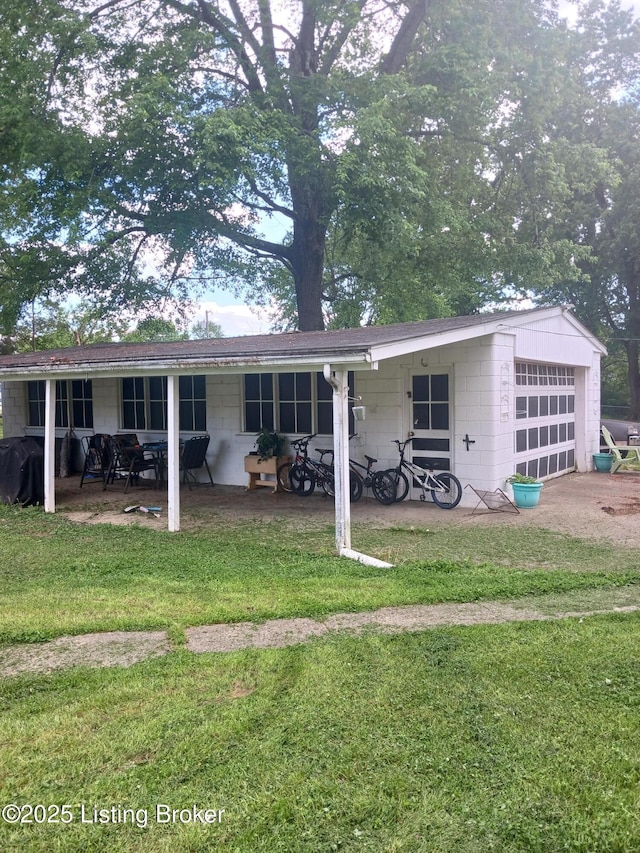 7702 Edna M Rd, Louisville, KY 40258 - back of house with a lawn, a garage, concrete block siding, and a patio