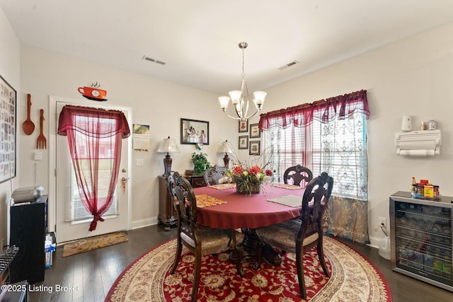 dining area with a chandelier, wood finished floors, wine cooler, and baseboards