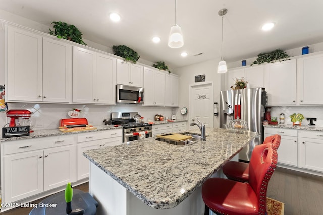 kitchen featuring appliances with stainless steel finishes, a sink, tasteful backsplash, white cabinets, and recessed lighting