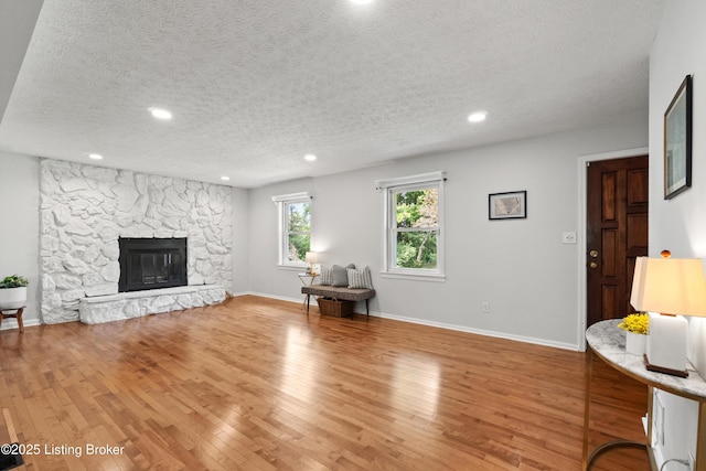 3304 S Camden Ln, Crestwood, KY 40014 - living area with a textured ceiling, light wood-style floors, recessed lighting, a stone fireplace, and baseboards