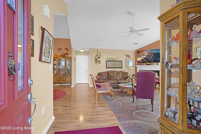 entrance foyer featuring vaulted ceiling, ceiling fan, baseboards, wood finished floors, and a textured ceiling