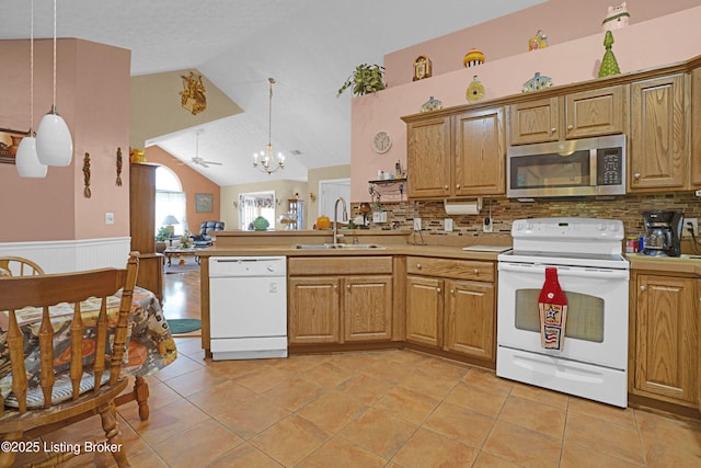 kitchen with white appliances, a sink, vaulted ceiling, decorative backsplash, and light countertops