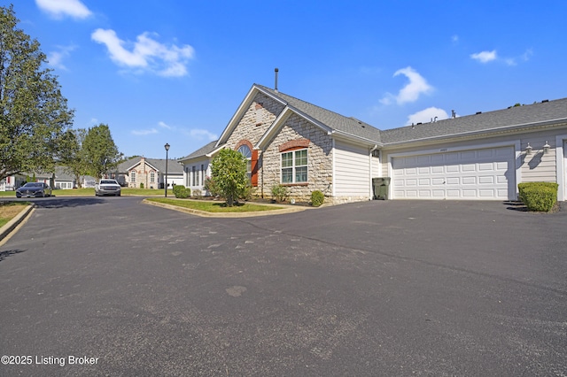 view of front of property with stone siding, driveway, and a garage