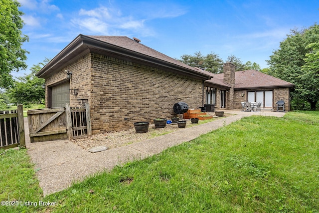 1093 W Bryan Rd, Elizabethtown, KY 42701 - back of property with a gate, brick siding, an attached garage, a patio area, and a chimney