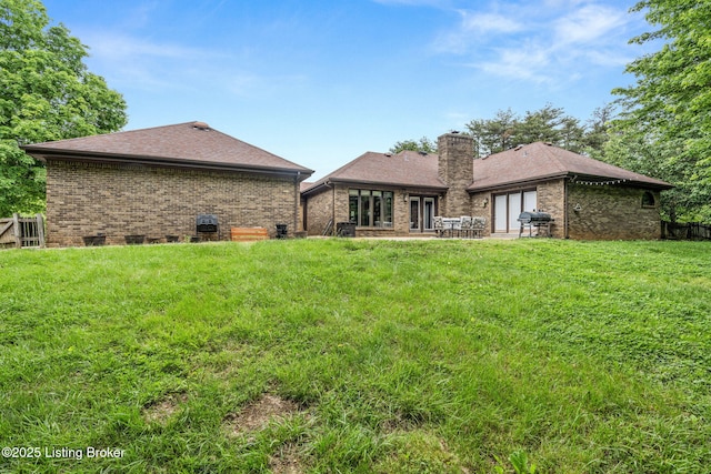 1093 W Bryan Rd, Elizabethtown, KY 42701 - back of property with brick siding, a chimney, a lawn, a patio area, and a shingled roof