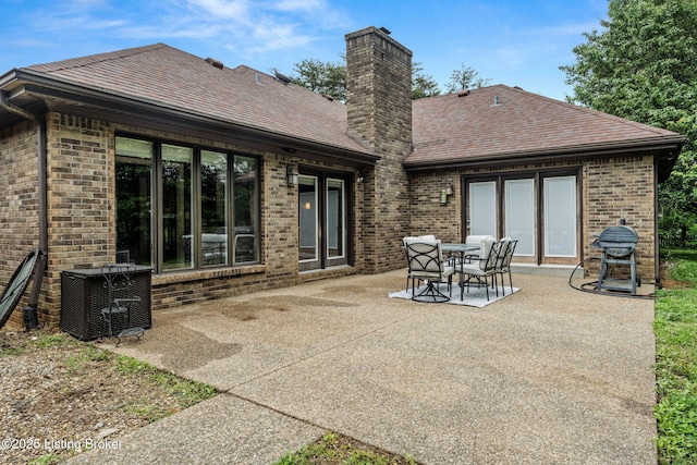 1093 W Bryan Rd, Elizabethtown, KY 42701 - back of property featuring brick siding, a chimney, a patio area, a shingled roof, and central AC