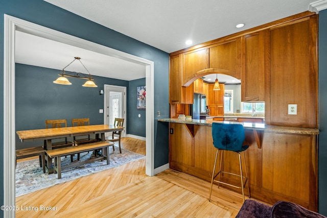 1093 W Bryan Rd, Elizabethtown, KY 42701 - kitchen with brown cabinets, light wood-style flooring, baseboards, decorative light fixtures, and a breakfast bar area